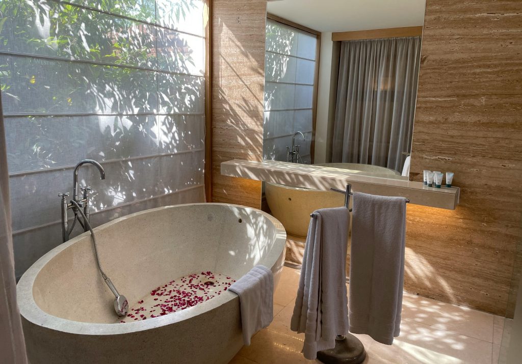 Private freestanding bathtub in a modern bathroom with soft light, stone walls, and full privacy